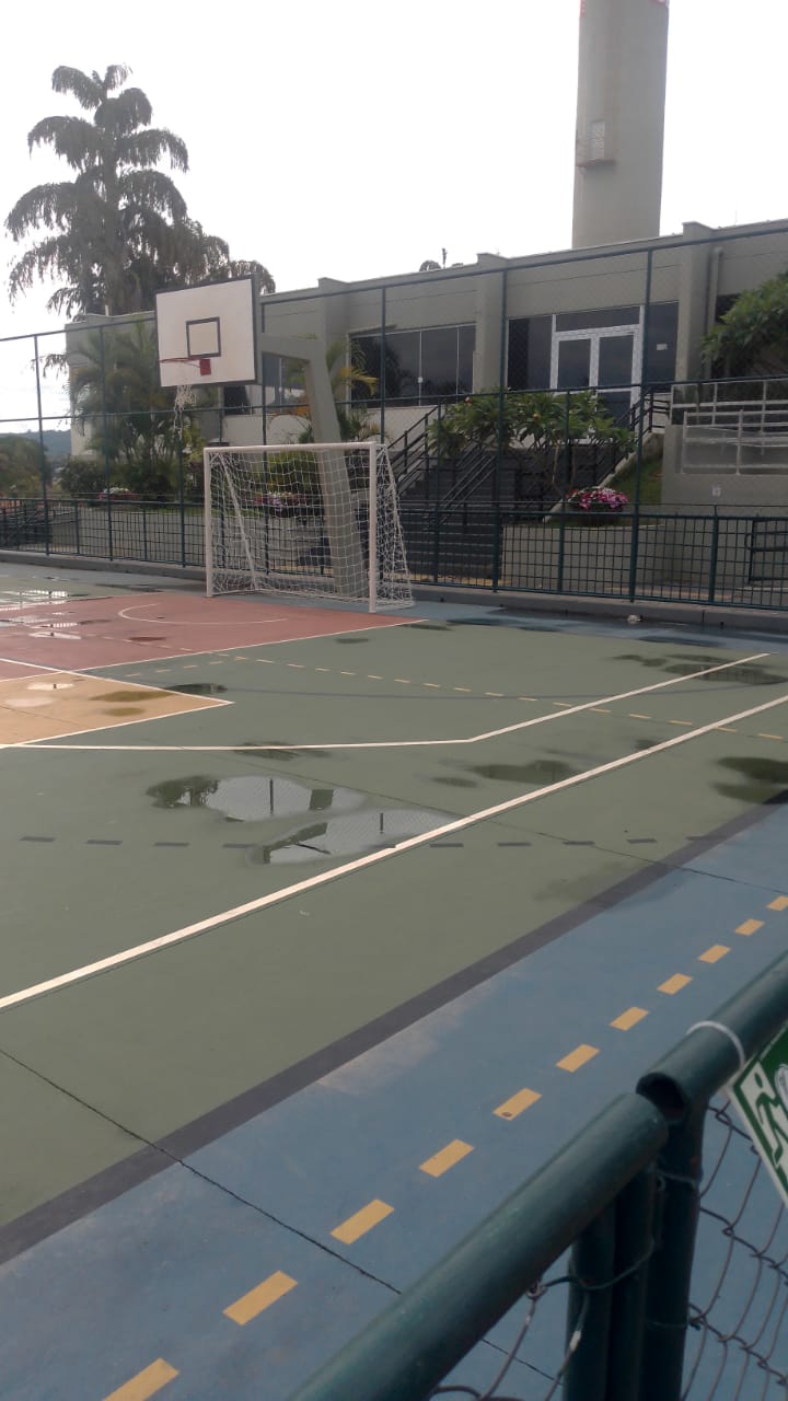 Quadra poliesportiva recém-pintada com piso multicolorido e demarcações nítidas