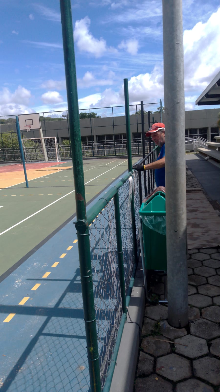 Trabalhador realizando manutenção e preparação de alambrado em quadra esportiva