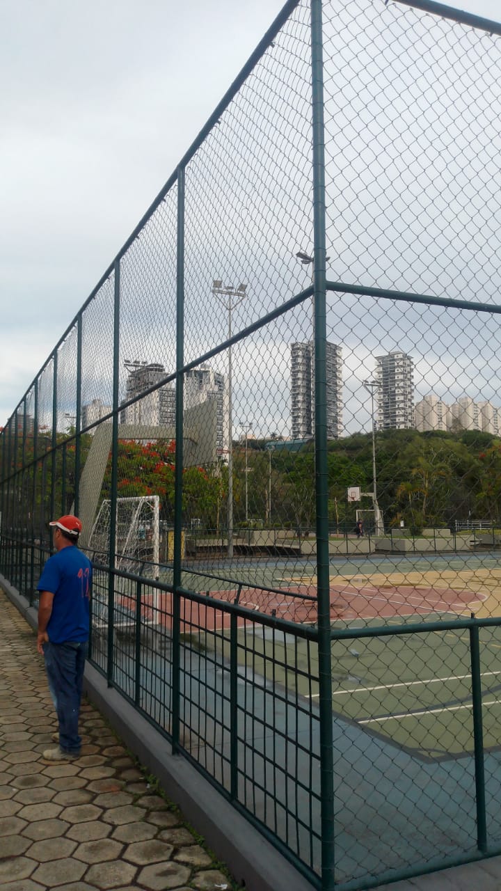 Quadra esportiva cercada por alambrado pintado de verde